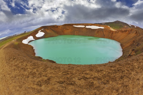 Krafla lake in the crater of an extinct volcano. Lake water bright green color. On the shores lie snowfields from last year