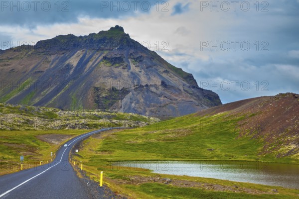 The road passes through the picturesque landscape in the mountains and lakes. Cloud Iceland in the summer