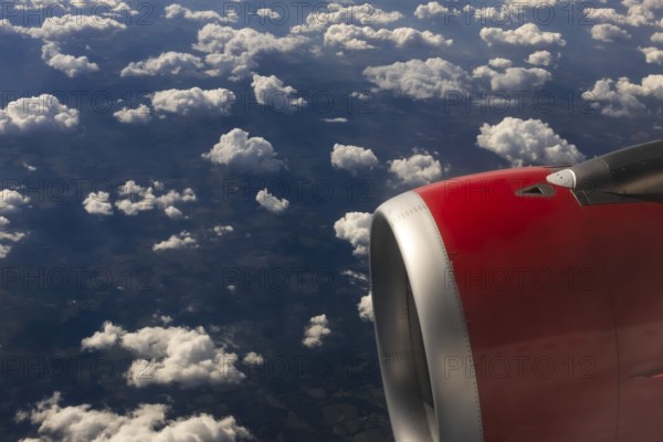 A colour landscape image looking out through airplane window showing land, cloud and sky