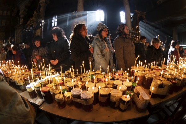 Blagoevgrad, Bulgaria - February 10, 2019: Worshippers light candles on jars with honey during a religious ritual marking the day of Saint Haralampi - the Orthodox patron saint of beekeepers - in the church of the Presentation of the Blessed Virgin