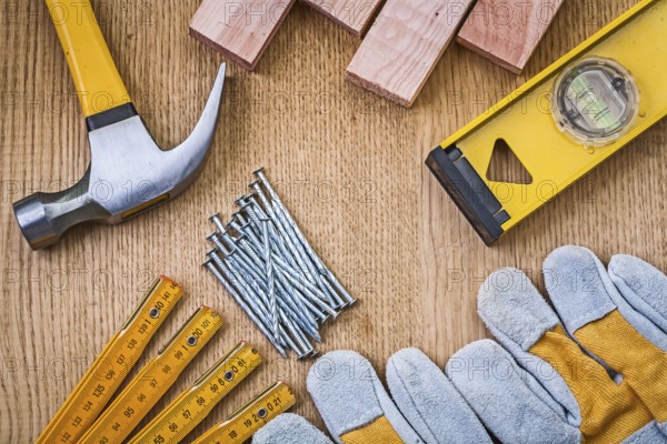 Set of tools claw hammer stack of nails safety gloves construction level wooden meter planks on wooden board