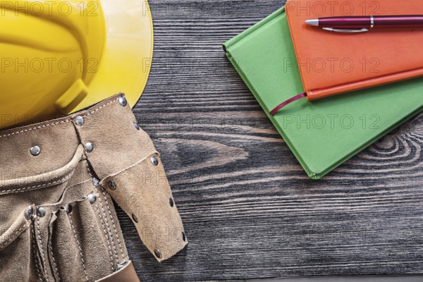 Collection of tool belt notepads pen building helmet on wooden board construction concept