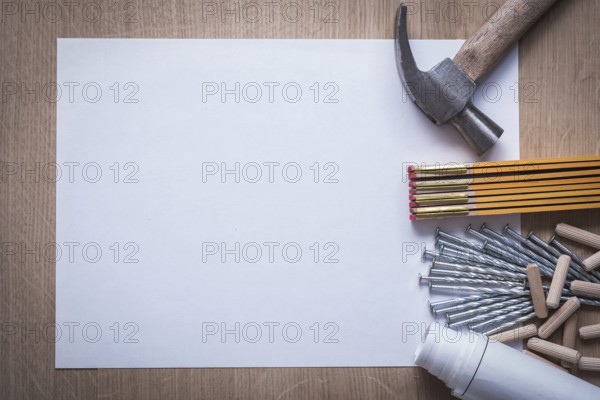 Wooden meter rolled construction plans blank paper metal nails claw hammer heap of fluted dowels on wood board copy space maintenance concept