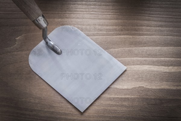 Steel glossy bricklaying trowel on wood board construction concept