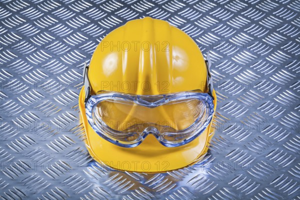 Safety glasses hard hat on grooved metal plate construction concept