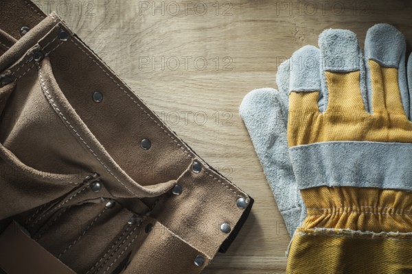 Leather building belt pair of protective gloves on wooden board