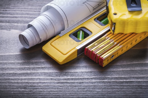 Measuring tape blueprints construction level and wooden meter on vintage wood board close up view maintenance concept