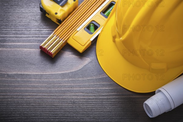 Tape-line blueprints construction level hard hat and wooden meter on vintage wood board maintenance concept