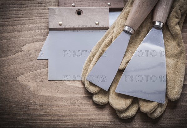 Two paint scrapers putty knifes working gloves