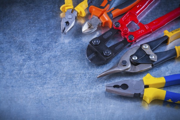 Set of bolt cutter tin snips cutting pliers gripping tongs on scratched vintage metallic surface construction concept