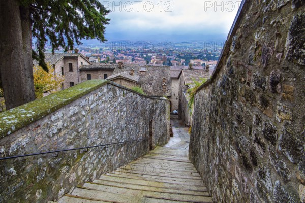Narrow cobblestone trail leads to the top of the hill. Autumn cloudy day. Magnificent Italy. The city of Gubbio is located in the Umbrian mountains. Ancient city with a rich history