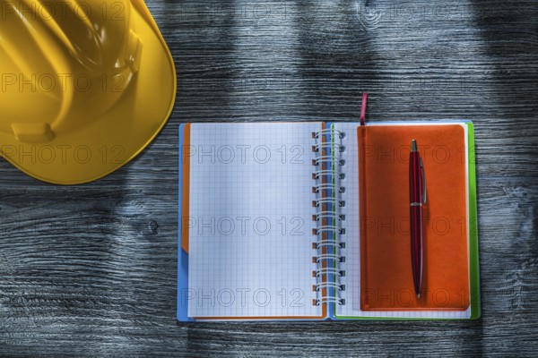 Spiral notepad pen building helmet on wooden board