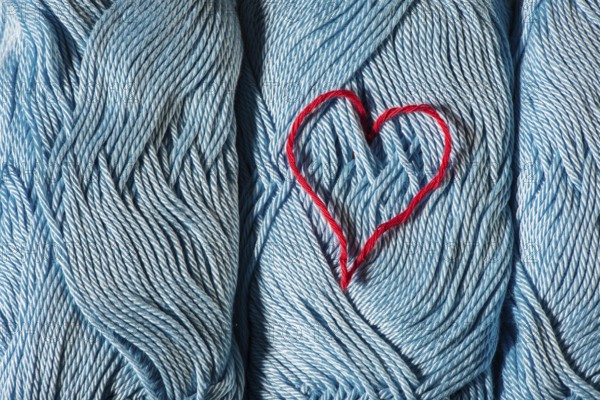 Knitted red heart on blue balls of yarn