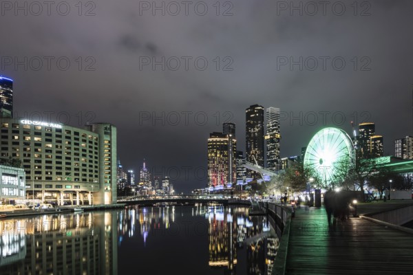 MELBOURNE, AUSTRALIA - JULY 5, 2024: Polly Woodside Park and ferris wheel and Melbourne skyline as seen at dusk from Melbourne Exhibition Centre in Melbourne, Victoria, Australia, Oceania