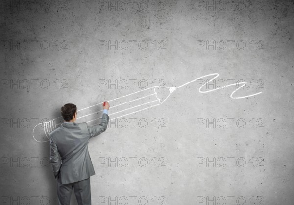 Rear view of businessman drawing sketches on wall
