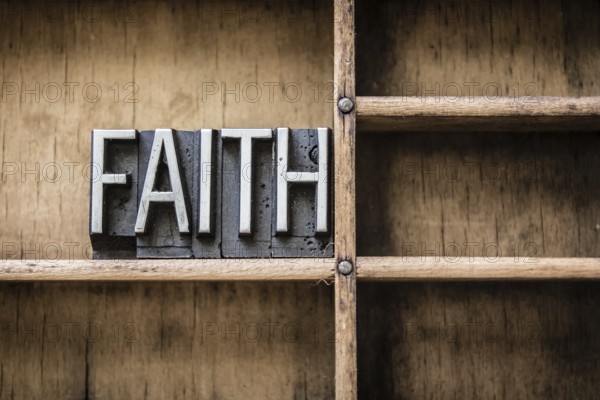 The word FAITH written in vintage metal letterpress type sitting in a wooden drawer