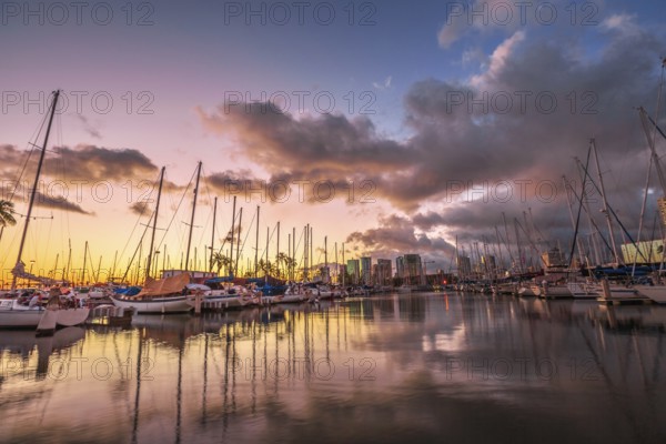 Dramatic landscape of sailing boats and yachts docked at the Ala Wai Harbor, the largest yacht harbor of Hawaii, reflecting in the sea at sunset. Honolulu, Oahu, Hawaii
