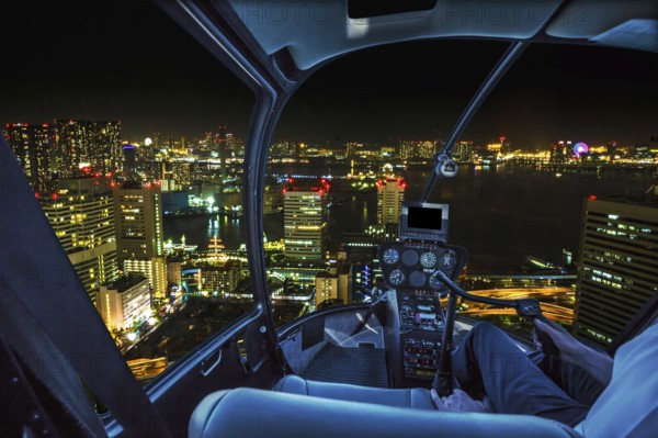 Helicopter flying over Tokyo cityscape, the Bay area with its bridges and Odaiba by night from Tokyo skyline in Japan