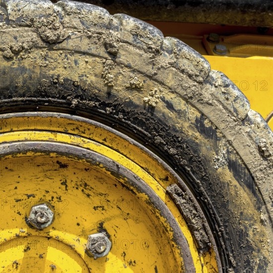 Extreme close up of tire bulldozer, yellow and covered with mud