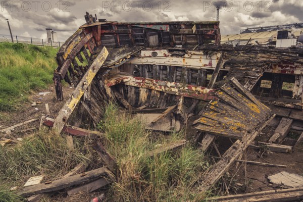 A derelict shipwreck with dark clouds over it, seen in King's Lynn, Norfolk, England, UK