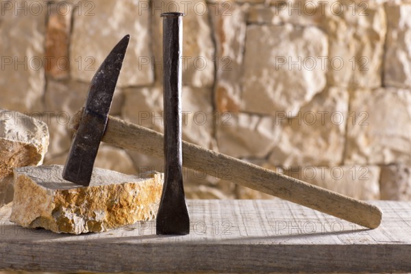 Hammer mason tools of stonecutter masonry work in a contruction stone wall