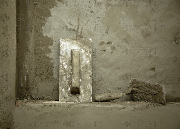 Dirty grunge cement trowel hand tools on fresh mortar wall