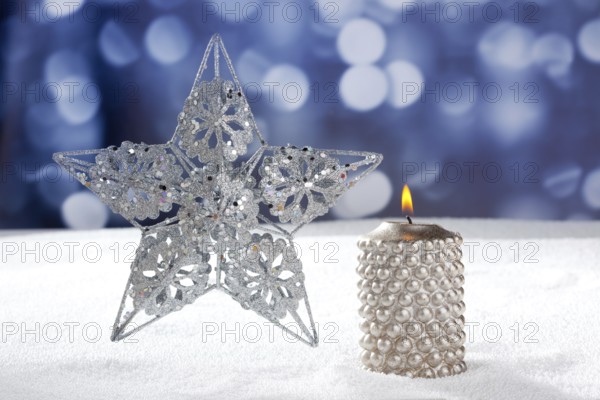 Christmas card of silver star and candle on snow and blue background
