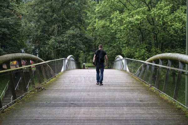 Man walking over a pedestrian bridge at Peterbos, Anderlecht, Brussels Capital Region, Belgium. Model released, staged situation