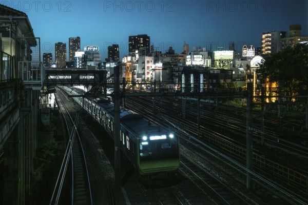 Train passes the Uguisudani railway station in Tokyo at night. Numerous hotels can be seen in the background