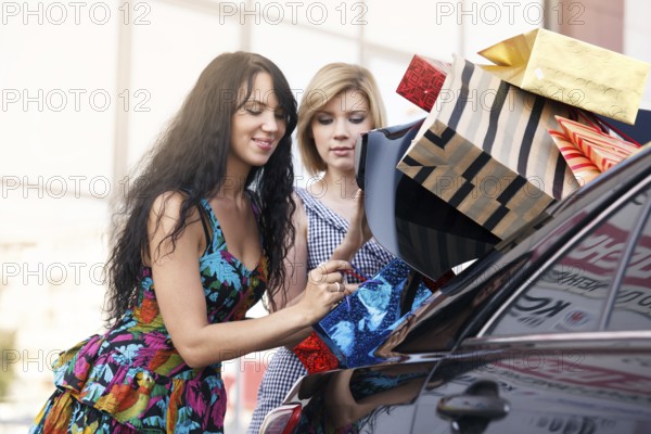 Girl-friends after shopping puts their bags in trunk