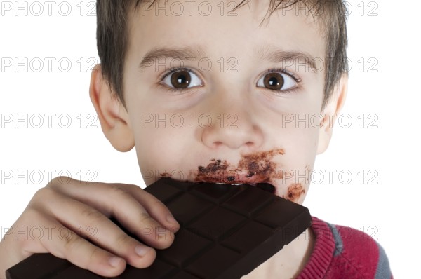 Smiling kid eating chocolate. Smeared stained with chocolate lips. White isolated