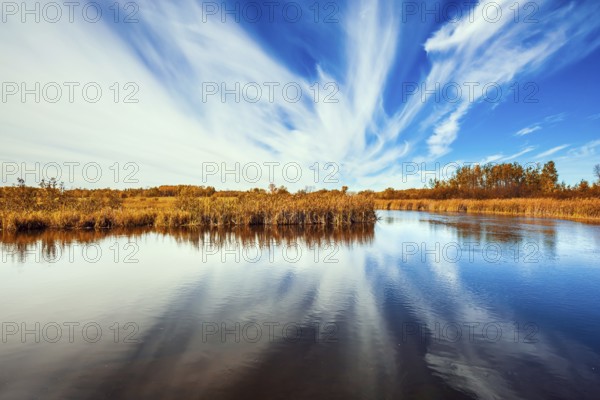 Cirrus clouds are reflected in the Winnipeg River. Wonderful autumn day in Manitoba. Old Pinawa Dam Park. The concept of ecological and recreational tourism