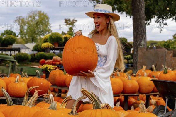 A beautiful European blonde female pics out some pumpkins and flowers for the upcoming fall festivals, Pineville, United States of America