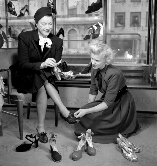 Shoe store in the 1940s. A woman in the shoestore on Hamngatan Stockholm 1948. She seems to look for something special in the new shoes she is looking for, and have several different pairs of shoes to try on. Sweden 1948. Conard ref 950