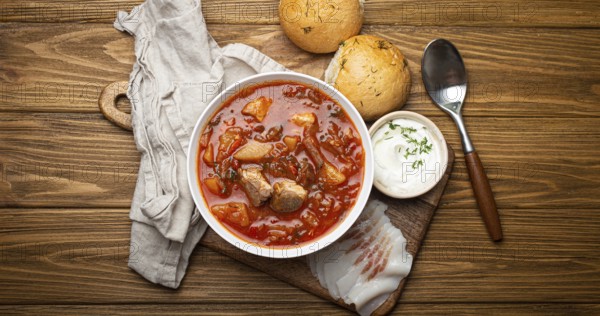 Ukrainian Borscht, red beetroot soup with meat, in white bowl with sour cream, garlic buns Pampushka and salo slices on rustic stone background. Traditional authentic dish of Ukraine, food photography, food photography