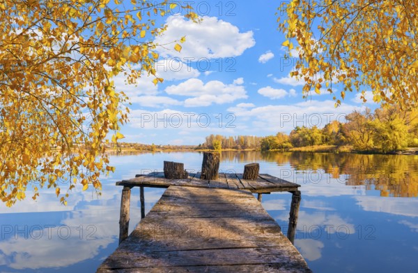 Wooden fishing pier on calm river in autumn