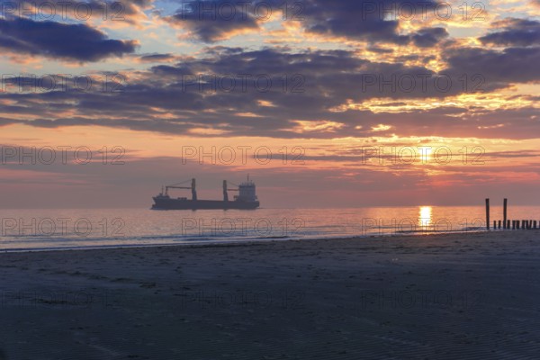 Sunset at the Seaside with a large ship and beautiful light and light reflections on the water.Beautiful Sunset at the Seaside with golden light and a ship in the background