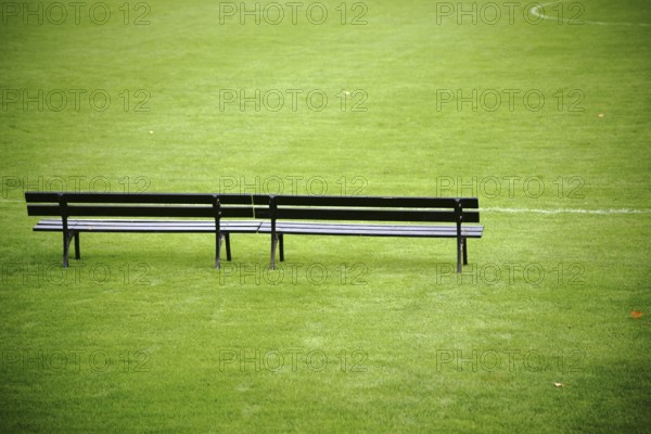 A trainer's bench stands at the edge of a football pitch in a football stadium