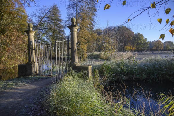 An open iron gate in a frosty garden, surrounded by autumnal colours and sunlight, borken, North Rhine-Westphalia, germany