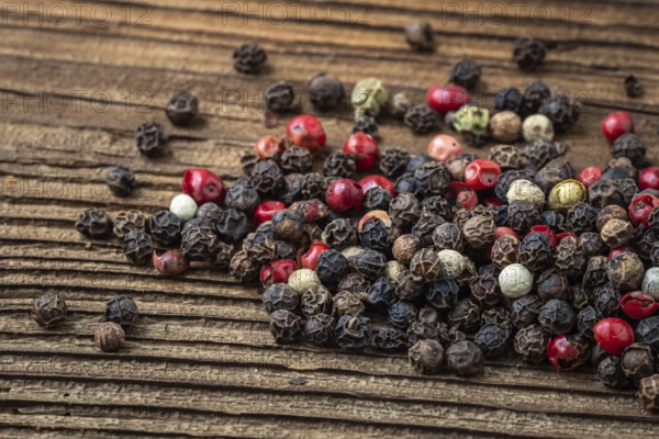 Peppercorns on dark rustic wooden background. Mix of different peppers