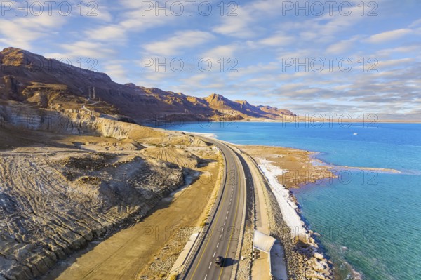 Sunset. Dead Sea photographed from a drone. Evaporated salt was deposited along the shore. Asphalt highway runs along the seashore. The winter in Dead Sea