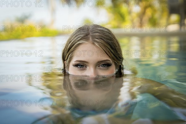 Young bikini model luxuriates in warm sun, cool pool, Yucatan Mexico vacation