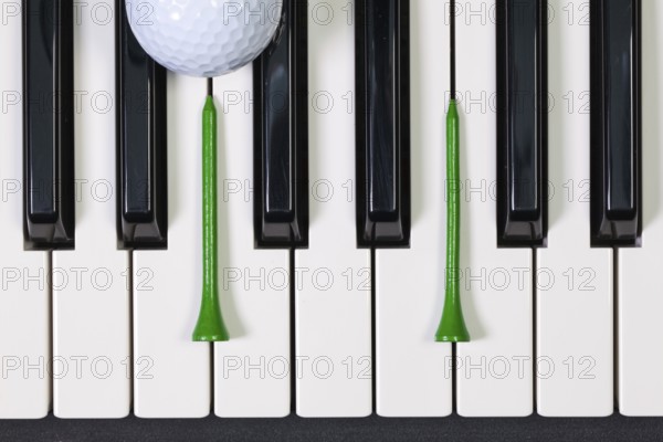 Virtuosic game - Piano keyboard and different golf balls and wooden tees