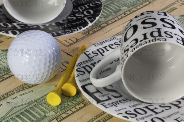Two empty coffee cups and golf equipments lying on US dollar banknotes