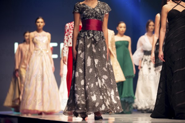Female models walk the runway in beautiful colorful dresses during a Fashion Show. Fashion catwalk event showing new collection of clothes. Unrecognizable people