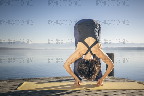 A pretty woman doing yoga at the lake