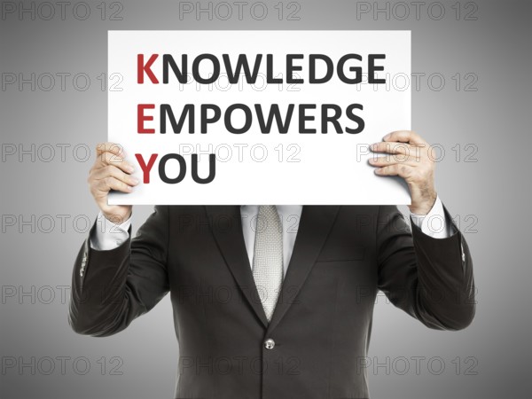 A business man holding a paper in front of his face with the text Knowledge Empowers You