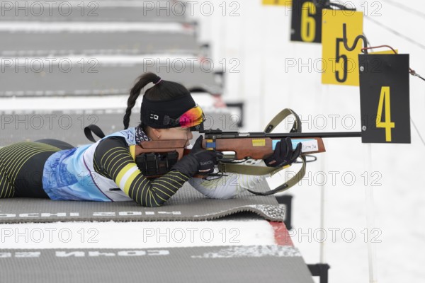 Sportswoman biathlete Lee Hyunju South Korea rifle shooting in prone position. Biathlete in shooting range of Open regional youth biathlon competitions East Cup. Kamchatka Peninsula, Russia, April 12, 2019, Europe