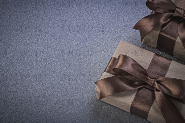 Giftboxes in brown wrapping paper on grey background celebrations concept