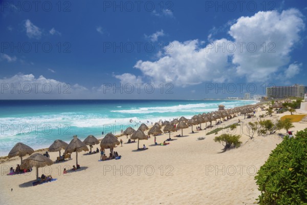 Umbrellas on a sandy beach with azure blue water on a sunny day near Cancun, Mexico, Central America
